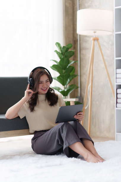 迷人的亚洲女性休息舒适的客厅和使用数码平板电脑，放松，沙发，生活方式图片下载