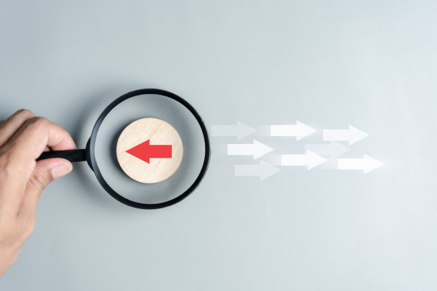 手持式放大镜聚焦于红色箭头和不同方向，与白色箭头面对相反的方向，用于业务中断和技术转型以及不同的思维理念概念。图片下载