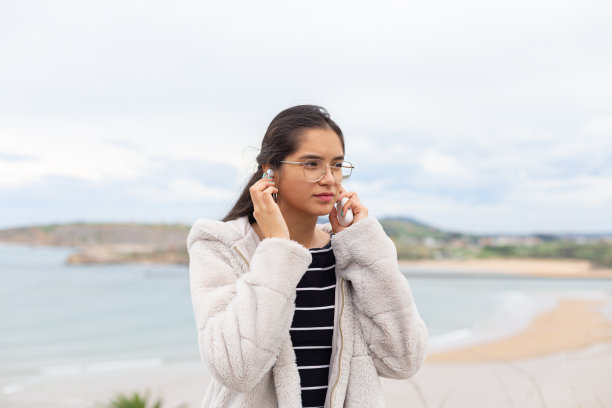 西班牙裔女士拿着智能手机，戴着无线耳机听音乐图片下载