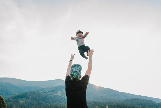 父亲的肖像把快乐的儿子抛在手上，在秋日的大自然中漫步。爸爸和孩子在山上玩。家人一起度假的概念。世界旅游日。图片下载
