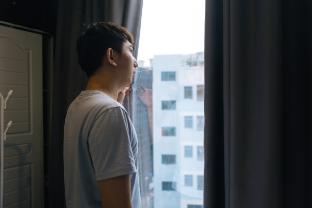 一个男人打开卧室的窗帘，寻找一种新的、充满希望的生活方式——一种健康的生活方式图片下载