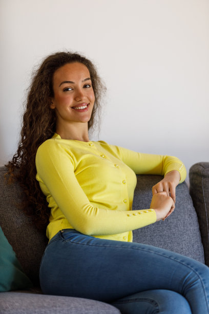 年轻女子坐在沙发上，只是放松和做白日梦图片下载