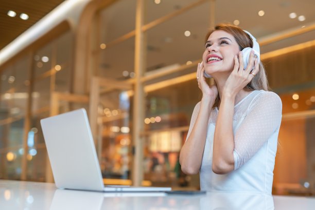 随意的商务女性，使用笔记本电脑和耳机，在带咖啡厅的工作空间进行电子学习和视频会议图片下载