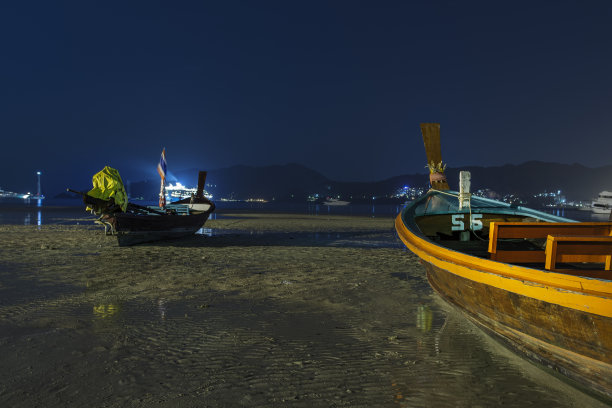 在普吉岛芭东海滩过夜。退潮时，长尾船停在沙滩上图片下载