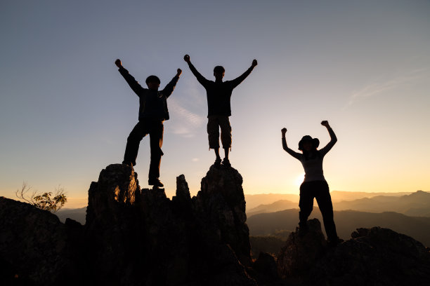 快乐团队的剪影以成功的姿态站在山顶，企业团队理念，企业胜利，实现企业目标。图片下载