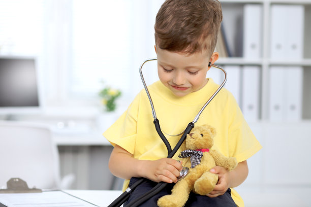 健康检查后快乐的小病人。小医生用听诊器检查玩具熊图片下载