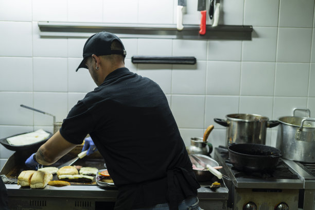 餐厅的厨师正在为准备汉堡包做切料图片下载