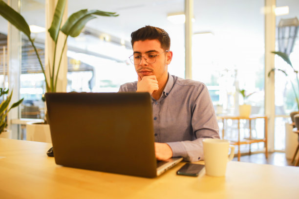 在咖啡馆用笔记本电脑远程工作的年轻人图片下载