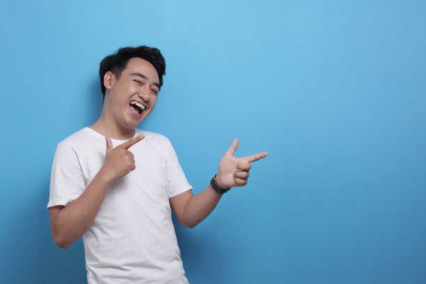 快乐的亚洲年轻人指着一边，展示一些有复印空间的东西图片下载