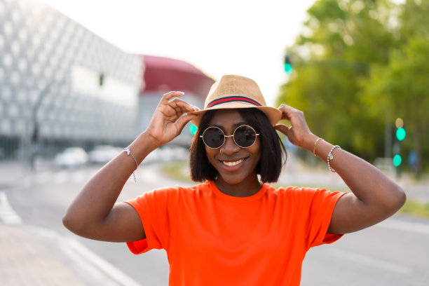 年轻的黑人女性游客在一个晚上穿着绿色t恤站在白墙前的肖像，生活方式的照片图片下载