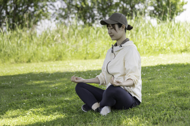 一个女人在公园的树荫下做冥想瑜伽图片下载