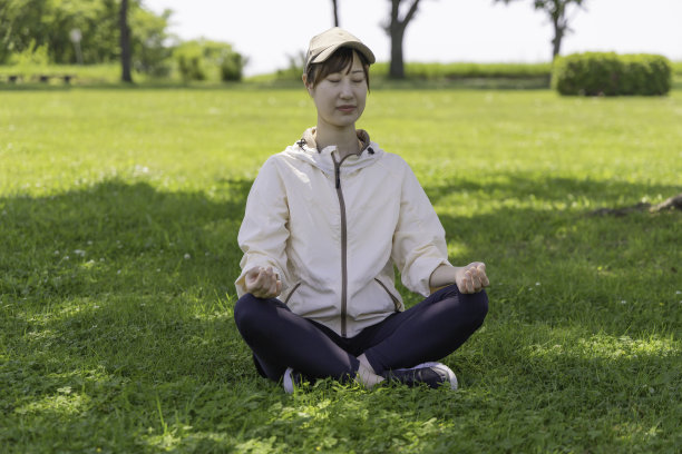 一个女人在公园的树荫下做冥想瑜伽图片下载