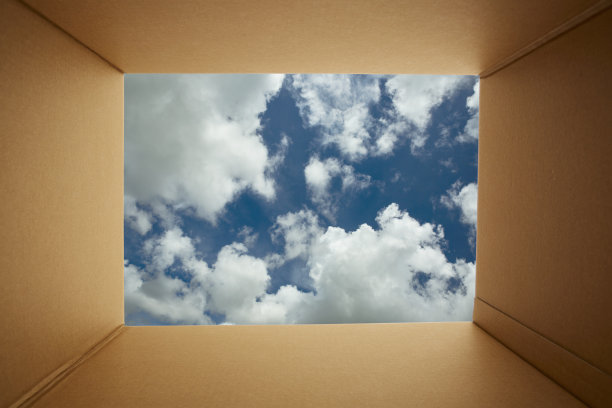 透过硬纸板打开盒子望向蓝天背景。图片下载