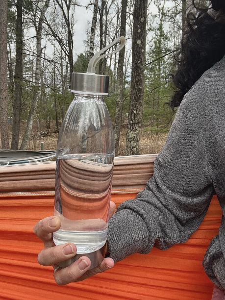 吊床上女子拿着塑料水瓶的部分照片。图片下载