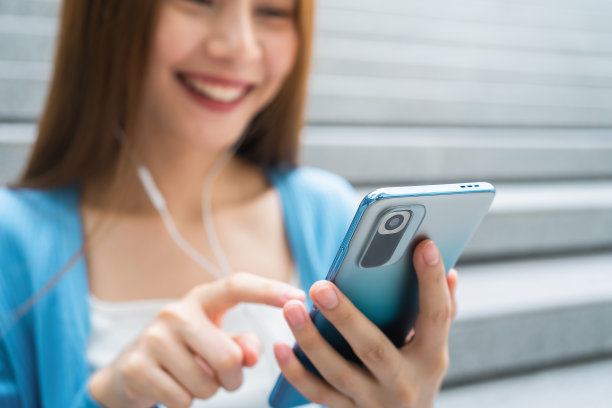 女性在公共场所使用智能手机，在闲暇时间。使用手机的概念在日常生活中是必不可少的。图片下载