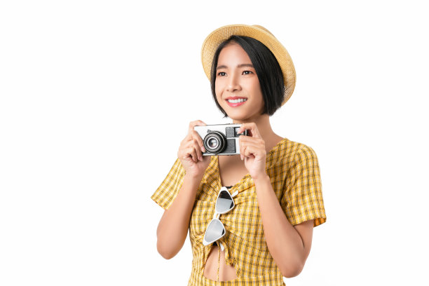 年轻的女游客拿着相机，看着白色的背景。图片下载