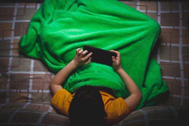 孩子手里拿着电话。小男孩在玩手机游戏。手的特写镜头。图片下载