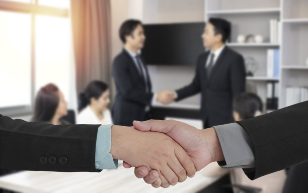 成功人士握手的图像，背景模糊，商务人士在现代办公室签订合同后握手。目标实现和成功的概念。图片下载