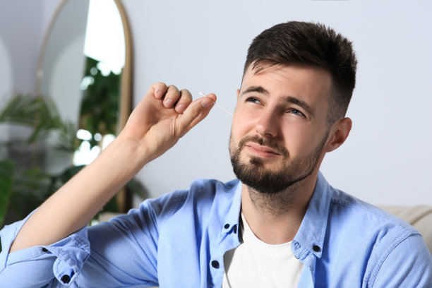 年轻人在家里用棉签清洁耳朵图片下载