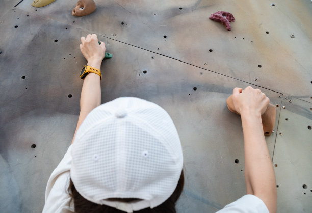 身份不明的女子在攀爬墙上抓着把手。图片下载