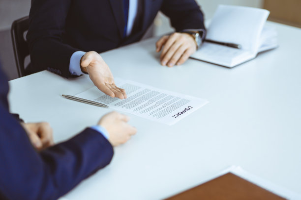 商务人士坐在现代办公室的办公桌前讨论合同。不知名的商人和同事，律师在谈判。团队合作及伙伴概念图片下载