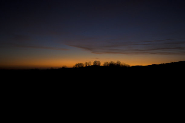 日落时山上树木的剪影与天空在品红，粉红色，蓝色水平柔和的颜色图片下载