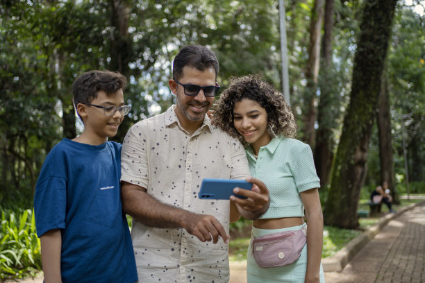 父亲和孩子在公园里玩智能手机图片下载