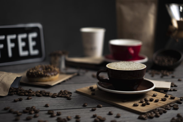 一张旧木桌上一杯咖啡的照片。桌子上有咖啡杯、咖啡豆、甜甜圈、咖啡袋、Chemex过滤咖啡和一个盘子。图片下载