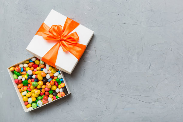 一套不同的糖果在一个纸盒与缎带彩色背景。节日的概念图片下载