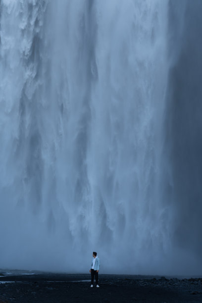 一名男子站在冰岛斯科加弗斯瀑布的底部图片下载