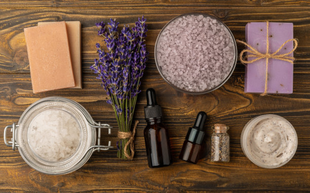薰衣草温泉。海盐、薰衣草花、精油、身体乳和手工肥皂。天然草药化妆品与薰衣草花在棕色纹理背景。放松和水疗的概念。文本空间图片下载