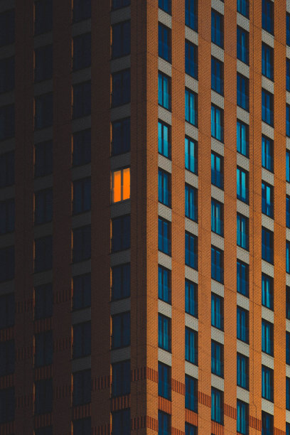 公寓大楼的夜晚，顶楼只有一扇蓝色的窗户图片下载