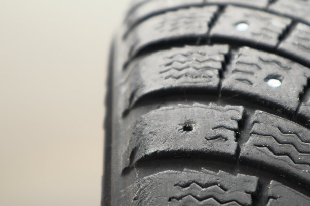 胎面磨损，冬季铆钉轮胎维修服务。更新丢失的饰钉。旧冬布满了轮胎。用过的雪地轮胎，盗钉不见了。图片下载