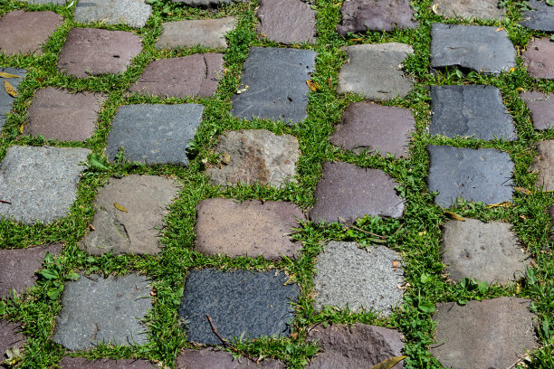 鹅卵石铺在绿草的路上。背景图片以城市规划、复古、旅行为主题图片下载