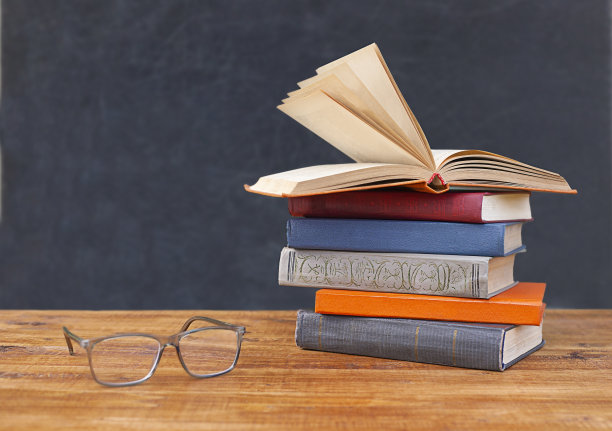 木桌上摆着一摞带眼镜的书图片下载