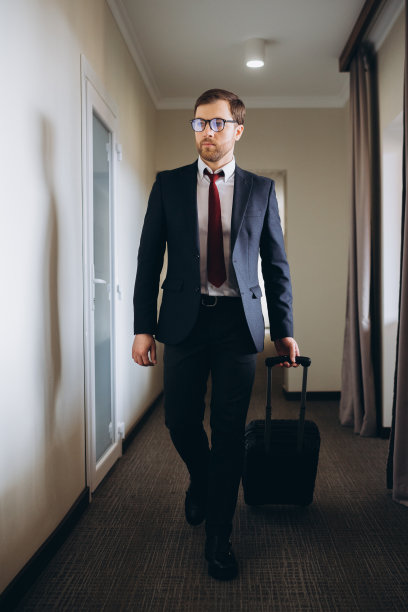 商人提着行李走在酒店走廊上。图片下载
