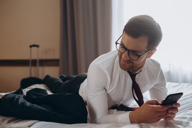 年轻的商人在酒店房间用手机工作图片下载