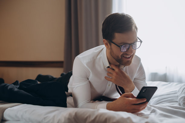 年轻的商人在酒店房间用手机工作图片下载