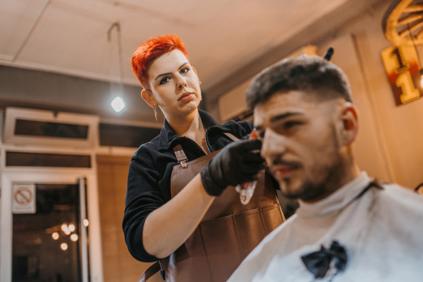 一位年轻的女理发师和一位年轻的顾客在理发店里图片下载