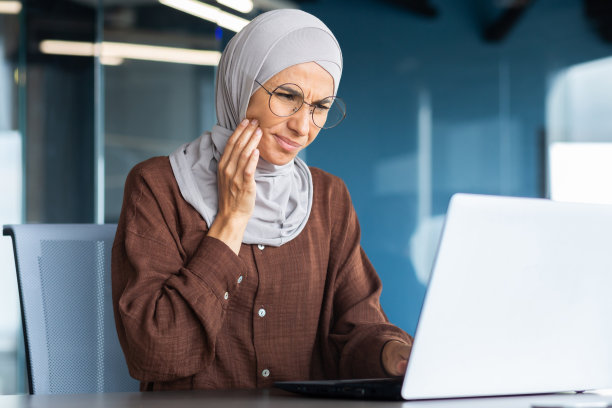 工作中牙痛的年轻女士，手扶脸颊按摩图片下载