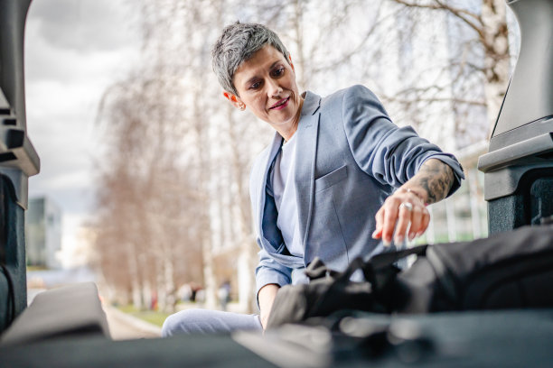 一位年长的妇女把行李打包在汽车的行李箱里图片下载