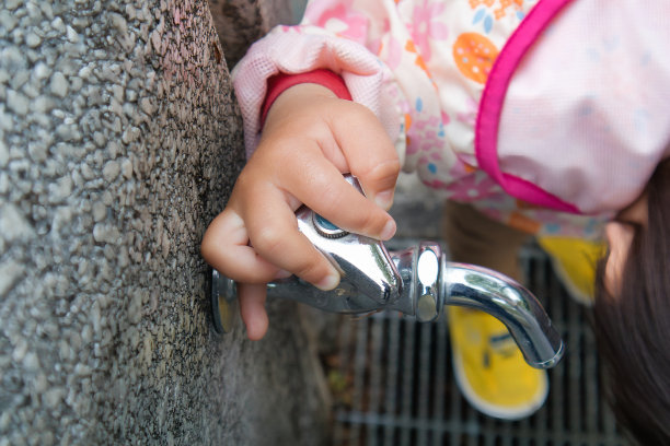 一个可爱的孩子在公园里用水龙头洗手的手图片下载