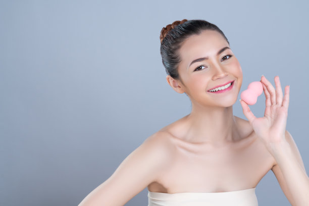 迷人美丽的女模特应用粉扑的面部化妆概念。图片下载