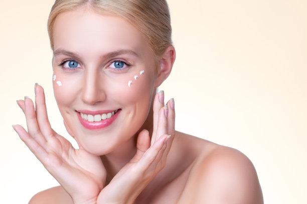 一位风度翩翩的女士在脸上涂抹保湿霜，以求完美肌肤图片下载