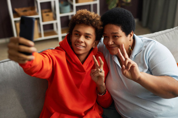 快乐的成熟女人和她十几岁的儿子在家里自拍图片下载