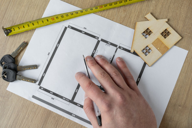 建筑师、室内设计师或房地产经纪人手持笔、房屋平面图、木制样板房、钥匙和卷尺。图片下载
