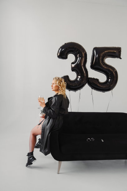 一个身穿黑衣的金发女郎，在沙发上喝着香槟。数字为35的气球图片下载