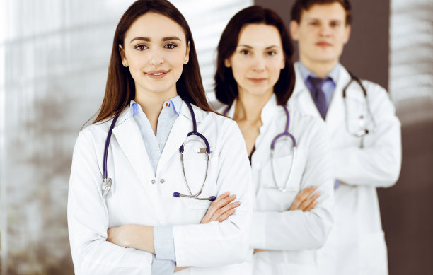 一群年轻的专业医生双臂交叉站在医院办公室里，准备帮助病人。医疗帮助，医疗保险，最佳疾病治疗和医学理念图片下载