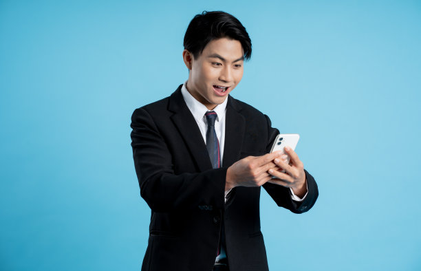 年轻商人在蓝色背景下使用手机的肖像图片下载