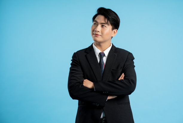 年轻商人的肖像在蓝色背景上摆姿势图片下载